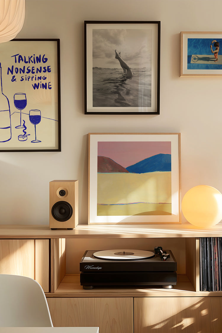 Ambiente moderno com móveis de madeira clara, vitrola e parede decorada com pôster artístico, fotografia em preto e branco e paisagem colorida minimalista — decoração contemporânea com quadros artísticos e atmosfera acolhedora.