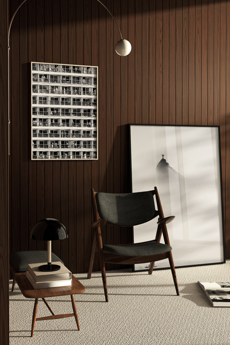 Ambiente moderno com parede de madeira escura, poltrona de design escandinavo e quadros em preto e branco – decoração elegante com arte fotográfica urbana e minimalista.