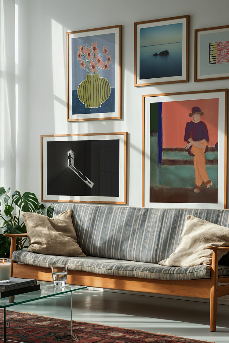 Sala de estar com design clássico e moderno, sofá de madeira com estofado listrado em tons neutros, decorado com almofadas bege. Parede em galeria com quadros decorativos emoldurados, incluindo arte abstrata, fotografia em preto e branco, ilustração de natureza morta e pintura figurativa. Mesa de centro em vidro, tapete oriental vermelho e plantas naturais ao lado, criando um ambiente aconchegante e sofisticado. Decoração de interiores, galeria de arte na parede, design moderno com toque vintage.