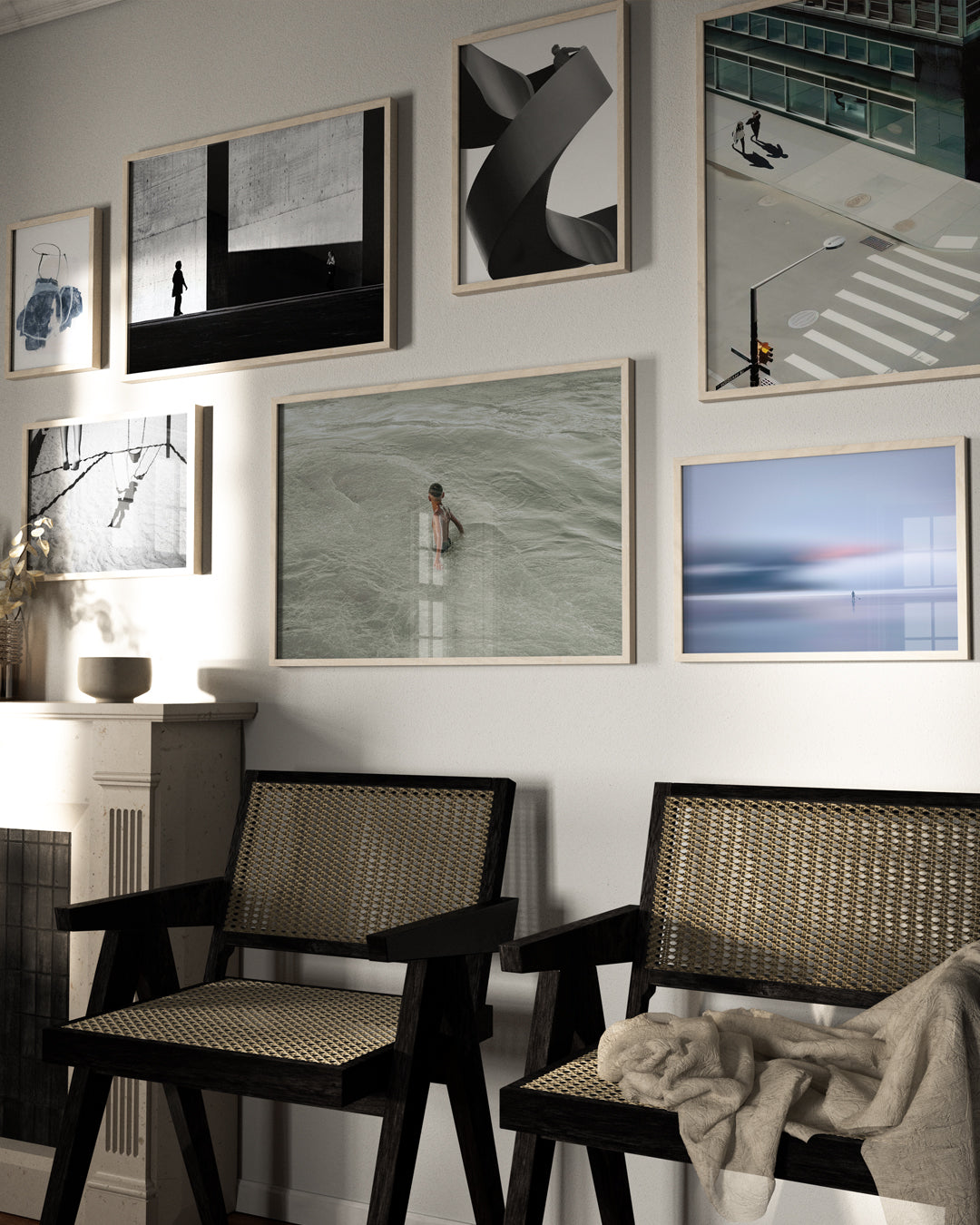 Sala com atmosfera contemporânea e acolhedora, destacando uma galeria com sete quadros de fotografias artísticas em diferentes estilos — desde retratos urbanos até composições minimalistas e abstratas. Abaixo, duas cadeiras de madeira escura com palhinha e um cobertor jogado trazem aconchego ao ambiente.